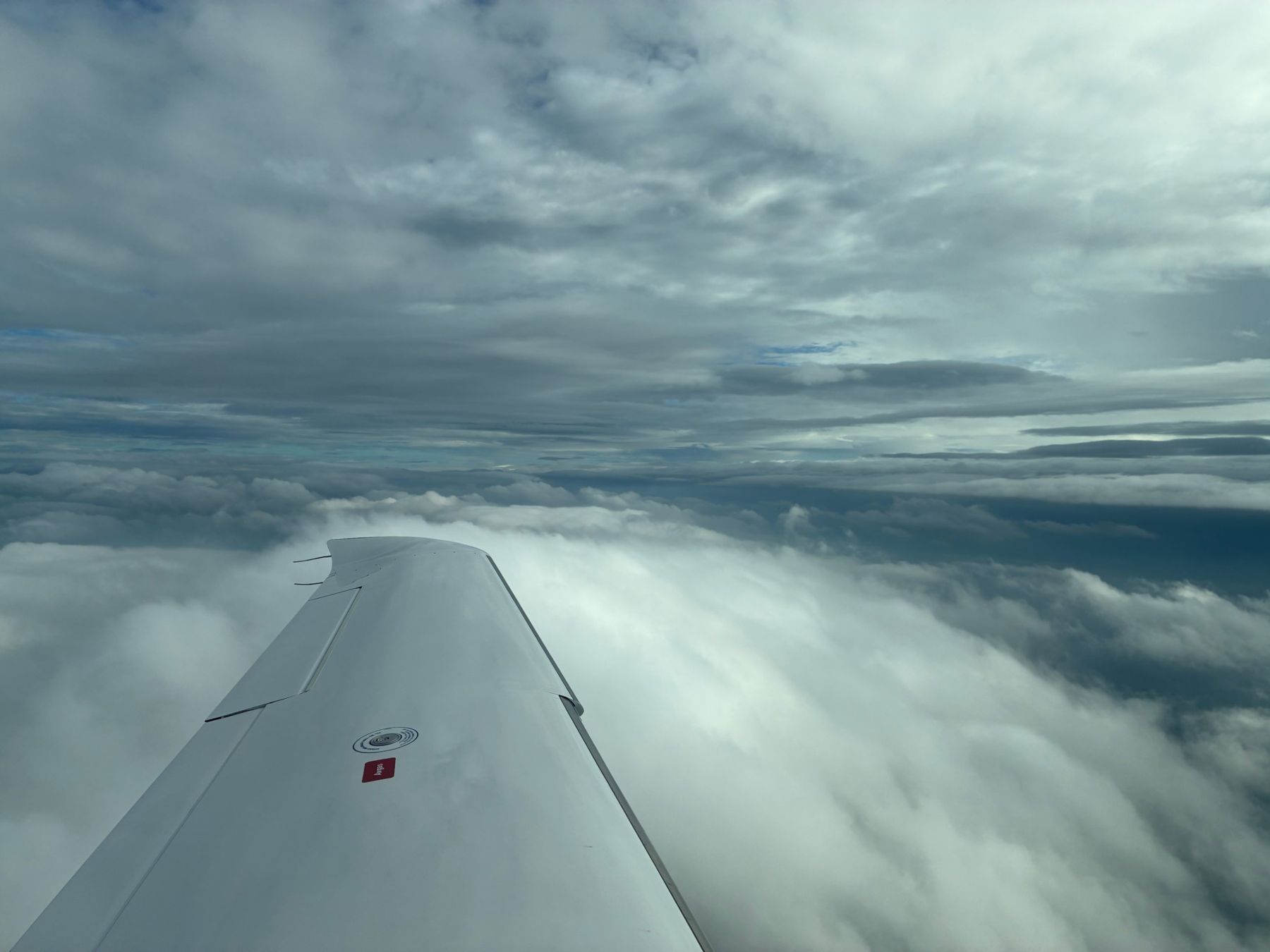 Blick über die Tragfläche auf eine Wolkendecke im Reiseflug